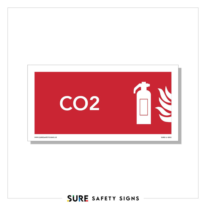 A red safety sign with white text and icons, commonly seen in Ireland, reads CO2 next to an icon of a fire extinguisher releasing gas towards flames on the right. At the bottom, the text SURE SAFETY SIGNS is visible.
