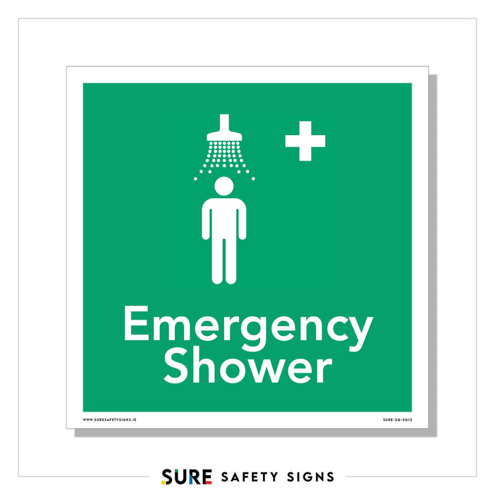 Green safety sign with a white figure under a showerhead, water streams depicted above. A white cross is on the upper right. Text reads Emergency Shower below the illustration, ensuring clear and visible signage in urgent situations.