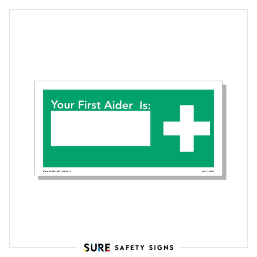 A green and white safety sign from Sure Safety Signs reads Your First Aider Is: with a blank space for a name, alongside a white medical cross. This customizable signage ensures your workplace always knows who the first aider is.