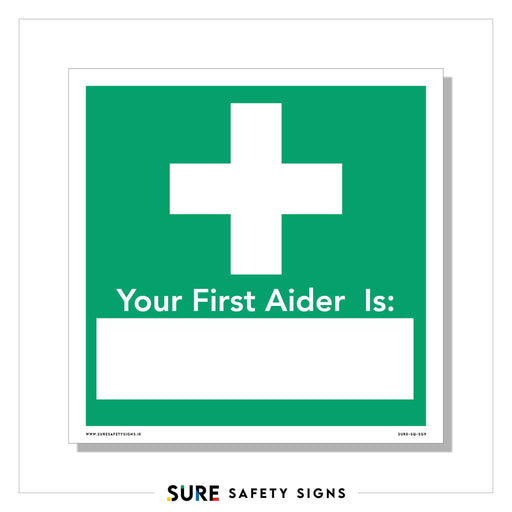 A green and white safety sign features a prominent medical cross above the customizable text Your First Aider Is: leaving a blank space for adding a name.
